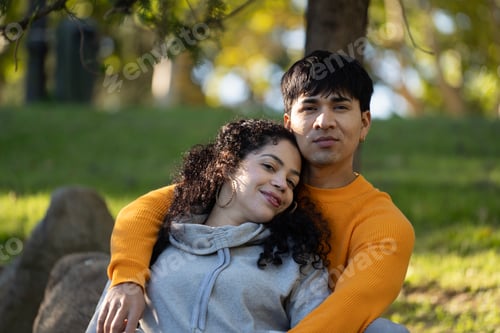 Preview: Happy hispanic couple relaxing and hugging in a park