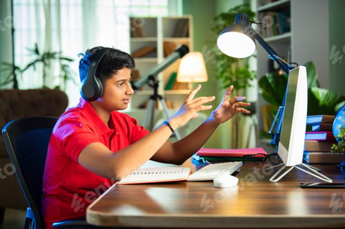 Preview: ndian Asian teenage student learning online with computer, headphones, and smartphone