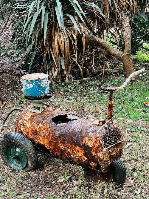 Preview: Old rusty water tank on wheels with a steering wheel stands in the garden
