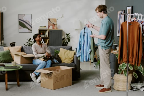 Preview: Diverse Couple Sorting Clothes for Donation during Home Decluttering