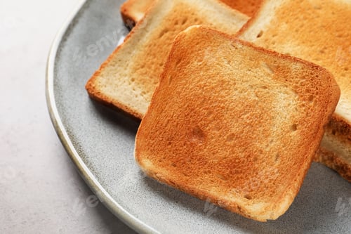 Preview: Plate with slices of delicious toasted bread on gray table, closeup