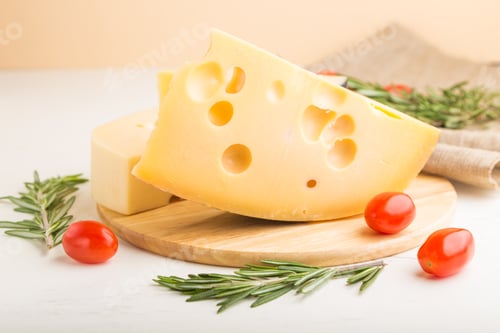 Vista previa: Various types of cheese with rosemary and tomatoes on wooden board on a white wooden