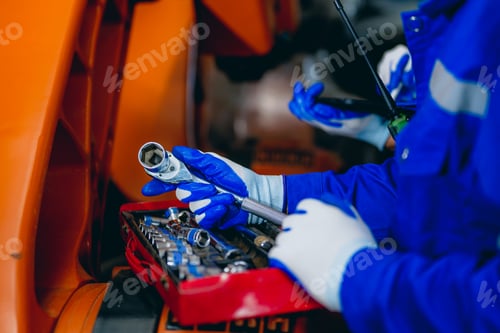 Preview: Professional maintenance worker with machine robotic arms at industrial factory