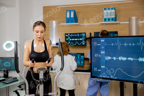 Preview: Female athlete who makes a physical effort on the stepper and has electrodes attached to it and her