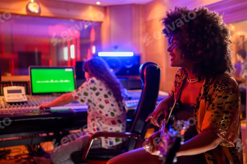 Preview: A multiracial bass player smiling and playing bass, recording session in a music studio.