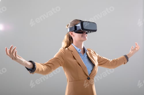Preview: Caucasian businesswoman wearing vr headset widening her arms, isolated on grey background