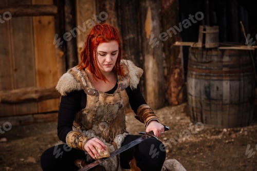 Preview: Red-haired woman is a Viking. Against backdrop of a village or an ancient settlement