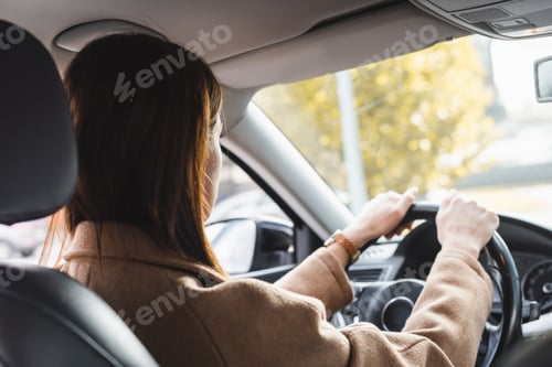 Preview: back view of woman steering car on blurred foreground