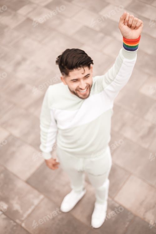 Preview: young man with lgbt bracelet raising his fist, shot from above