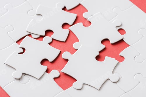 Preview: unfinished jigsaw near connected white puzzle pieces on red