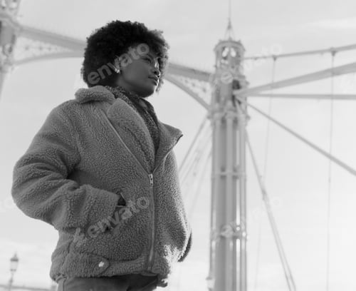 Preview: Nostalgic black and white portrait of black woman standing on bridge.