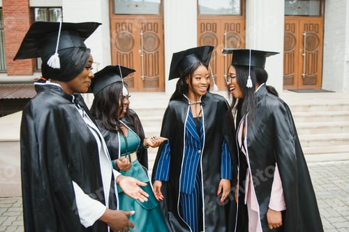 Preview: young graduates standing in front of university building on graduation day