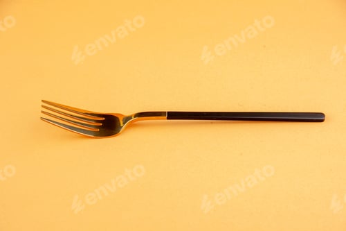 Preview: Front view of elegant shiny stainless fork on golden background with free space