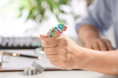 Preview: Woman squeezing colorful slime in office, closeup. Antistress toy