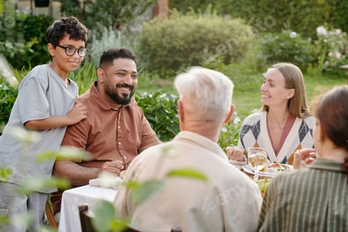 Preview: Multiethnic Family Gathering Outdoors Enjoying Meal and Smiling Together