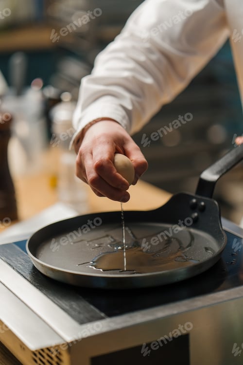 Preview: Professional kitchen chef prepares fried eggs for breakfast