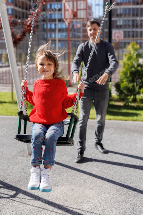 Preview: Father and daughter spending time at playground, playing and dad pushing child on the swing.