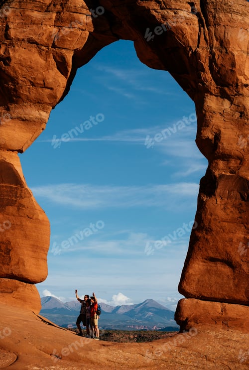 Preview: Hikers celebrate under a majestic red rock arch.