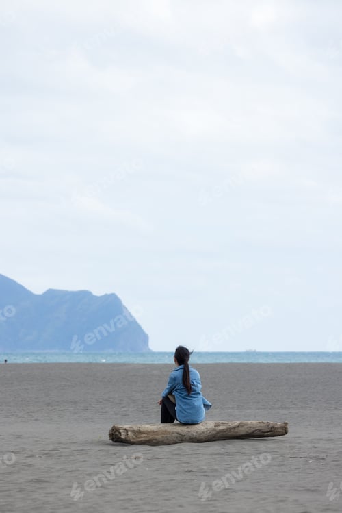 Preview: Woman sit on the beach and look at the Guishan at Yilan