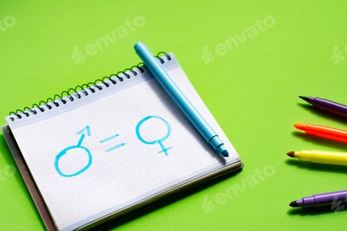 Preview: Children's drawing in a notebook with the symbol of women and men and an equal sign. Concept: equali