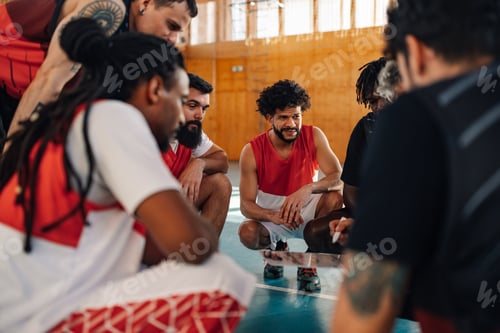 Preview: Diverse male basketball team and elderly coach discussing tactic during practice