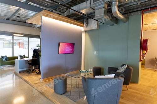Preview: Armchairs in front of television set in lobby of modern illuminated office