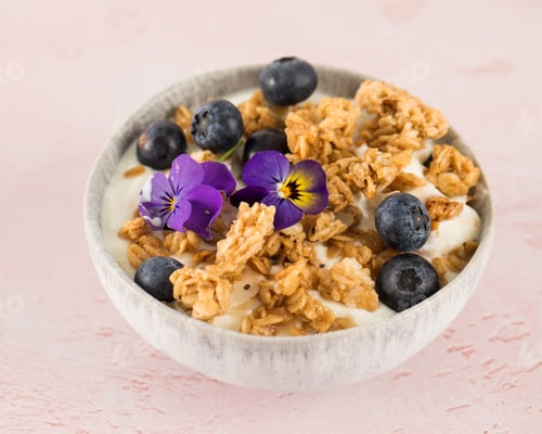 Preview: A healthy nutritious breakfast of natural yoghurts, granola and fresh berries on pink background.