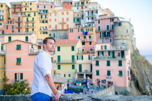 Preview: Young tourist man with great view of stunning village of Manarola, Cinque Terre, Liguria, Italy