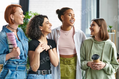 Preview: young and happy woman with coffee to go looking at stylish multiethnic female friends standing