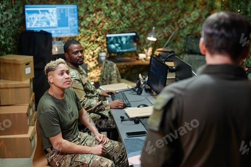 Preview: Group of young intercultural officers of surveillance room looking at speaker