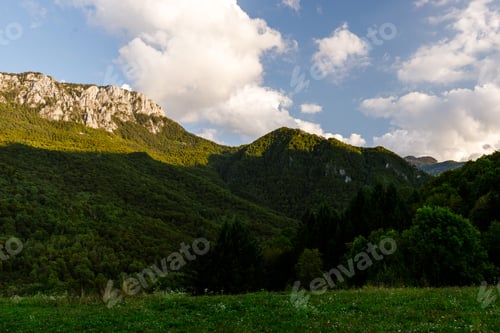 Preview: Scenic mountain landscape during golden hour with lush greenery and soft clouds