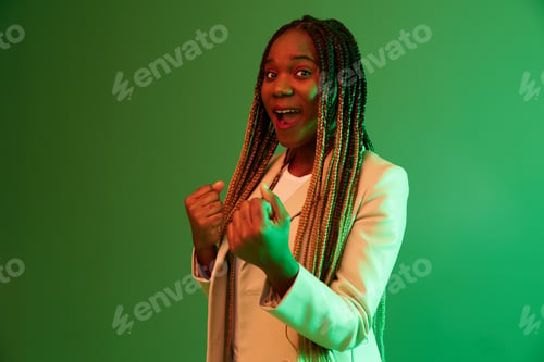 Preview: African american woman portrait business smile on green background in neon light, color mixed light