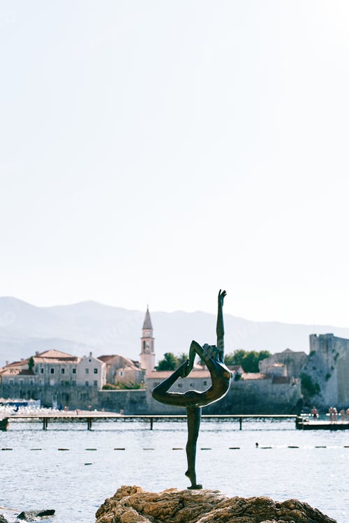 Preview: Sculpture of a ballerina on a stone by the sea against the backdrop of the old town of Budva