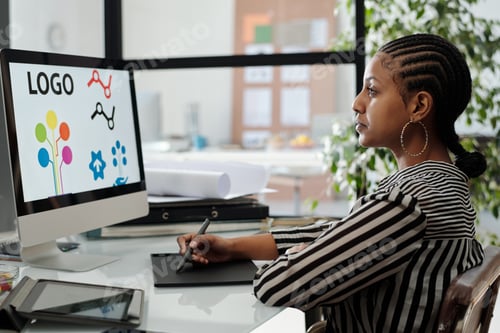 Preview: Serious African American female webdesigner working over new project by desk