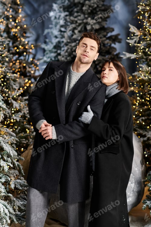 Preview: A beautiful couple wrapped in winter coats celebrates Christmas in a snowy pine forest
