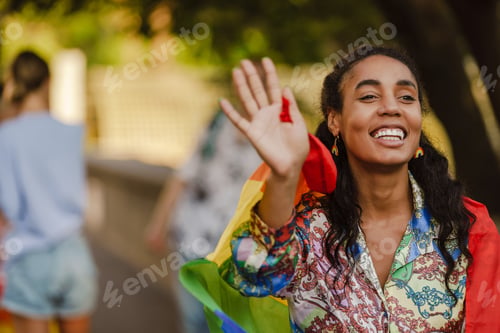 Preview: Black woman smiling and holding rainbow flag during pride parade
