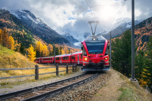 Preview: Red modern electric train traveling along a railway in mountains