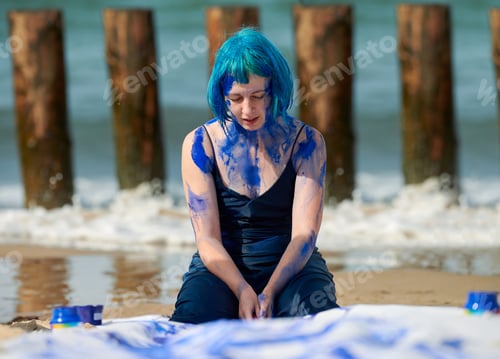 Preview: Artistic blue-haired woman performance artist in dress smeared with blue gouache paints on her body