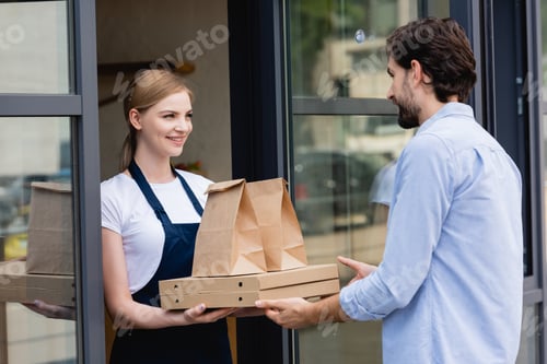 Preview: Attractive waitress giving pizza boxes and paper bags to man at entry of cafe