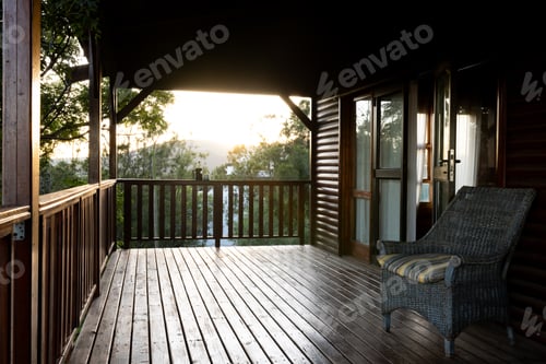 Preview: Balcony of log cabin with armchair and mug of coffee on sunny day