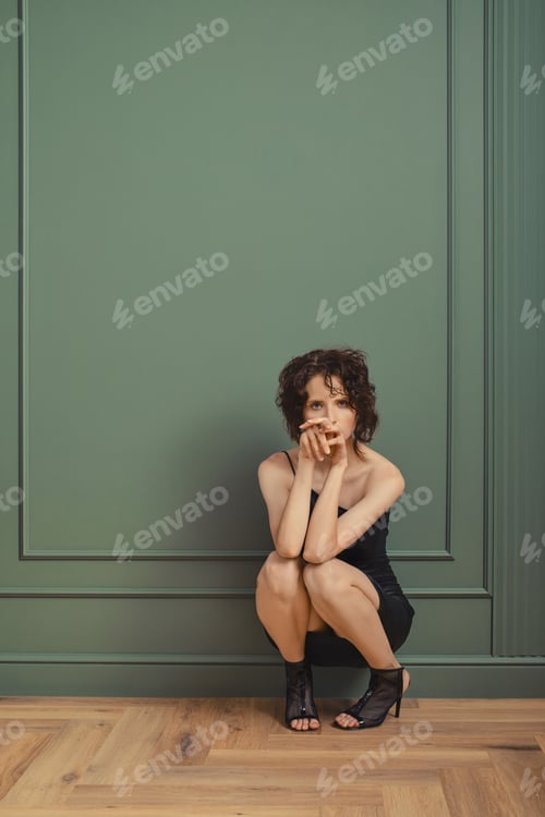 Preview: Cute woman in faux leather dress sits on squats