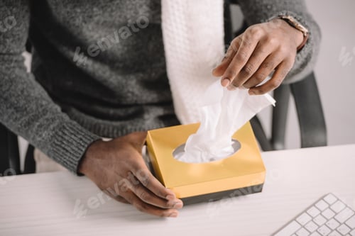 Preview: cropped view of african american man taking napkins from box at workplace