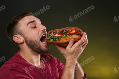 Preview: Young man eating tasty burger on color background