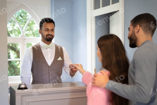 Preview: Receptionist Taking Credit Card From Couple Receiving Payment For Accomodation