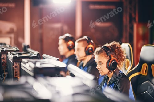 Preview: Young professional cybersport team wearing headphones participating in eSport tournament, playing