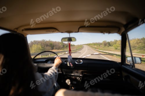 Preview: A woman is driving a vintage car through a picturesque landscape, feeling the breeze and enjoying th