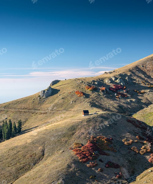 Preview: Beautiful autumn mountain landscape with colorful trees and a lonely house on a hill.