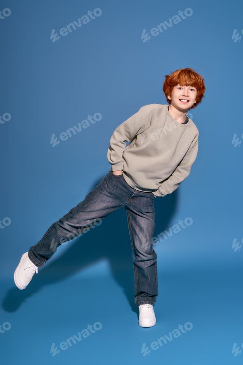 Preview: Stylish little boy showcases playful fashion against a vibrant blue background