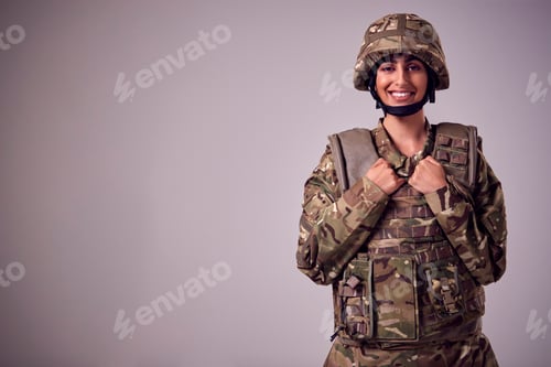 Preview: Studio Portrait Of Smiling Young Female Soldier In Military Uniform Against Plain Background