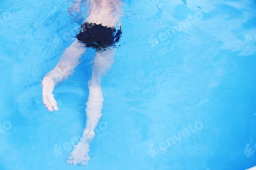 Preview: boy swims in the pool. boy learning to swim. feet in the pool close